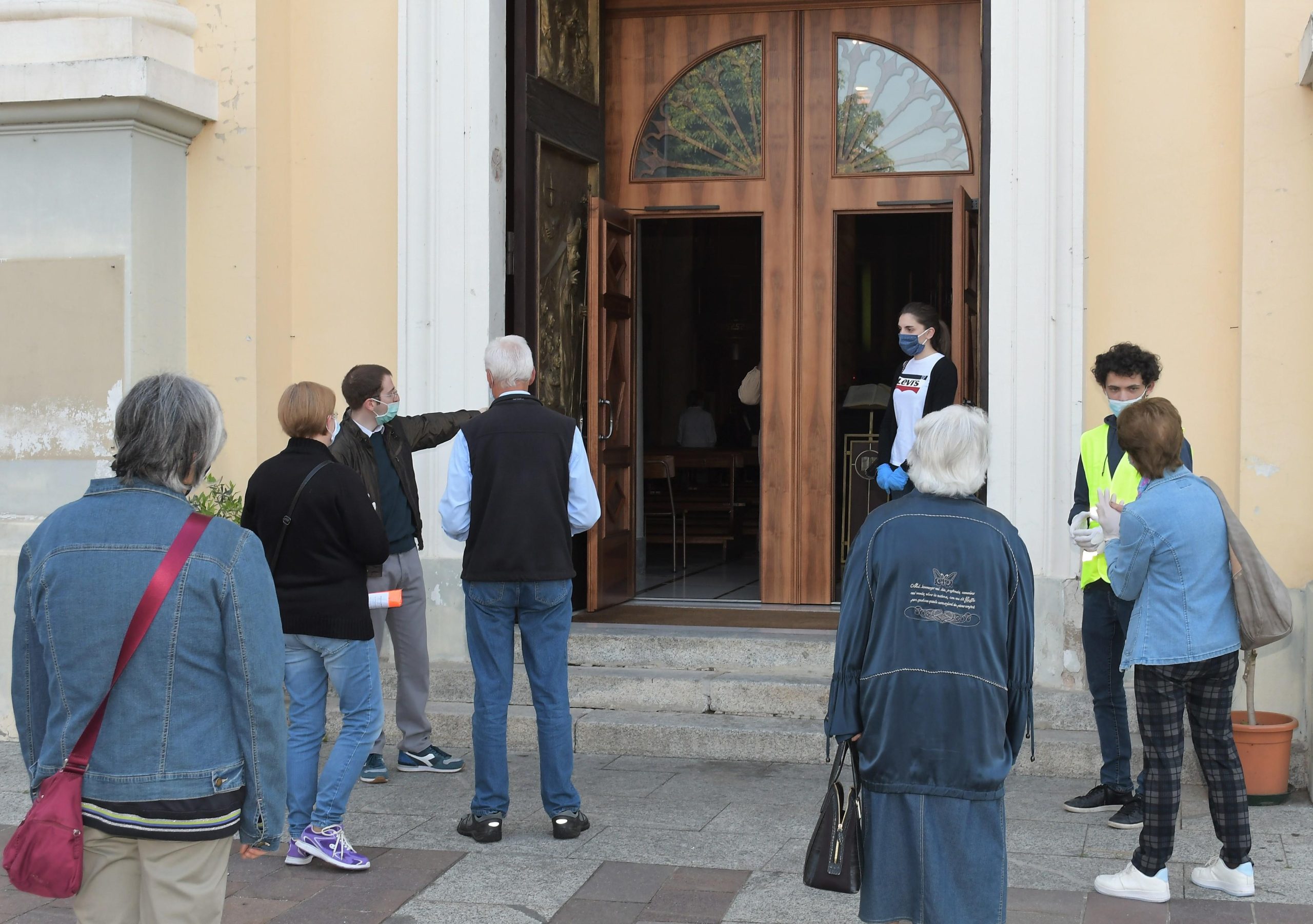 Volontari accolgono fedeli in chiesa (Agenzia Fotogramma)